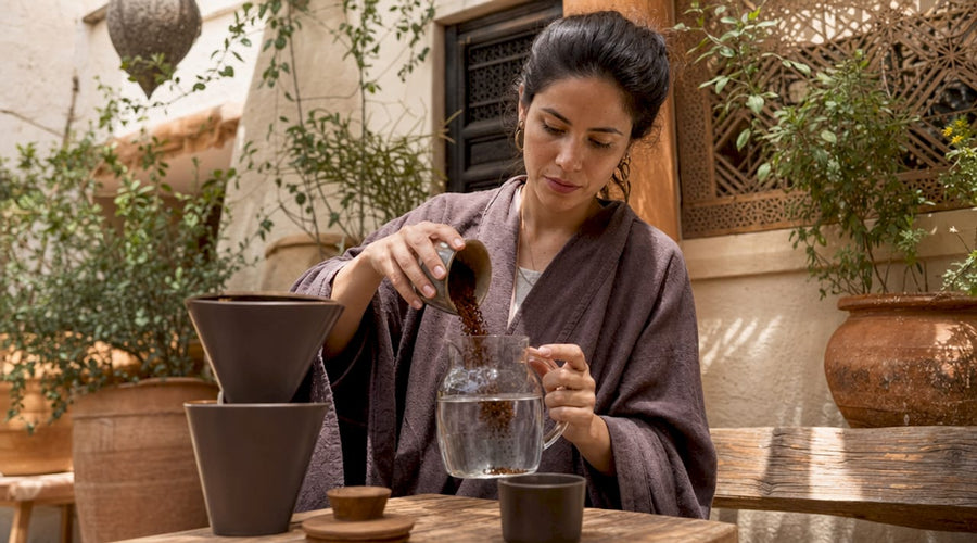 Una mujer prepara café frío en la cocina, disfrutando del aroma mientras mezcla los ingredientes con cuidado.