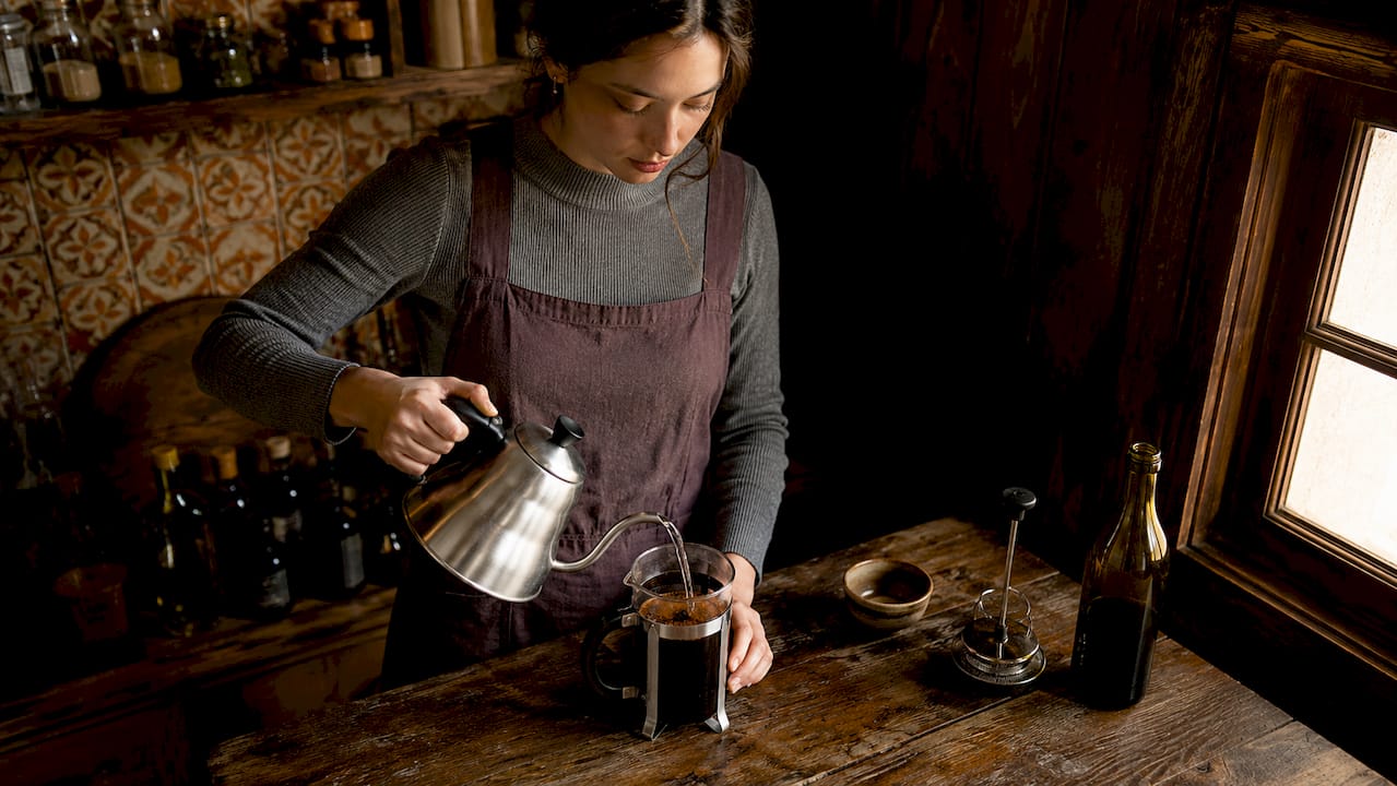 Una mujer disfruta de preparar café con una prensa francesa en la comodidad de su hogar.