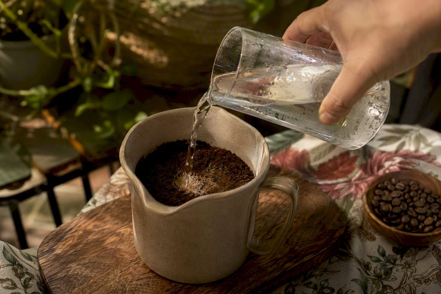 Mão despejando água sobre o pó de café para cold brew