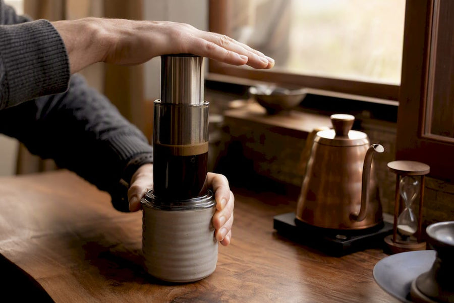 Mão pressionando lentamente a cafeteira AeroPress