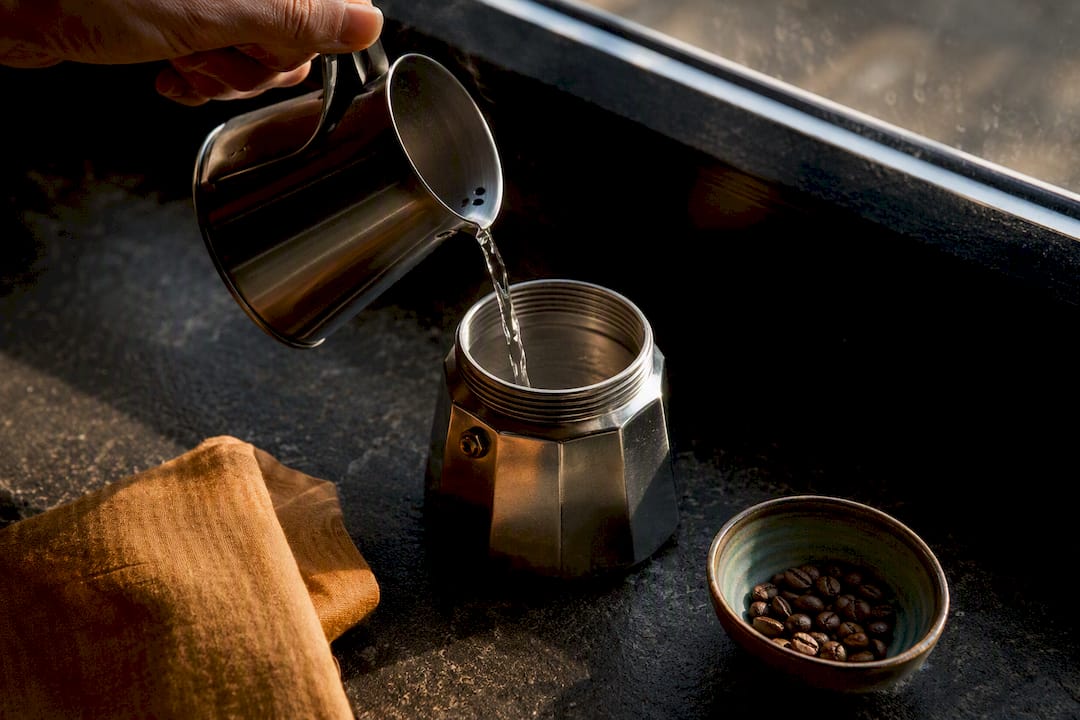Versement d'eau chaude dans une cafetière moka