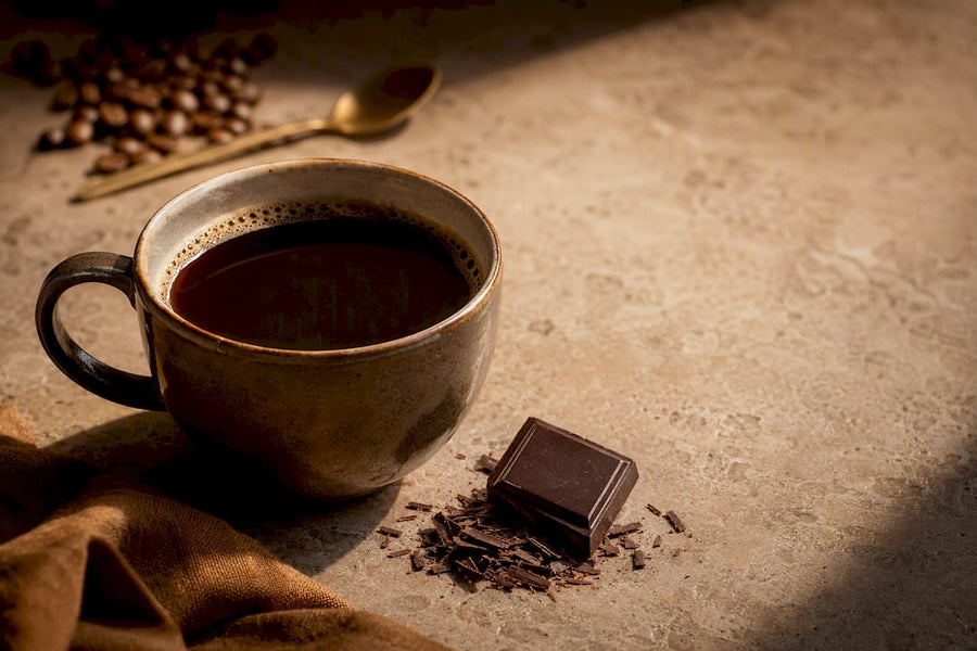 Taza de café acompañada de chocolate negro