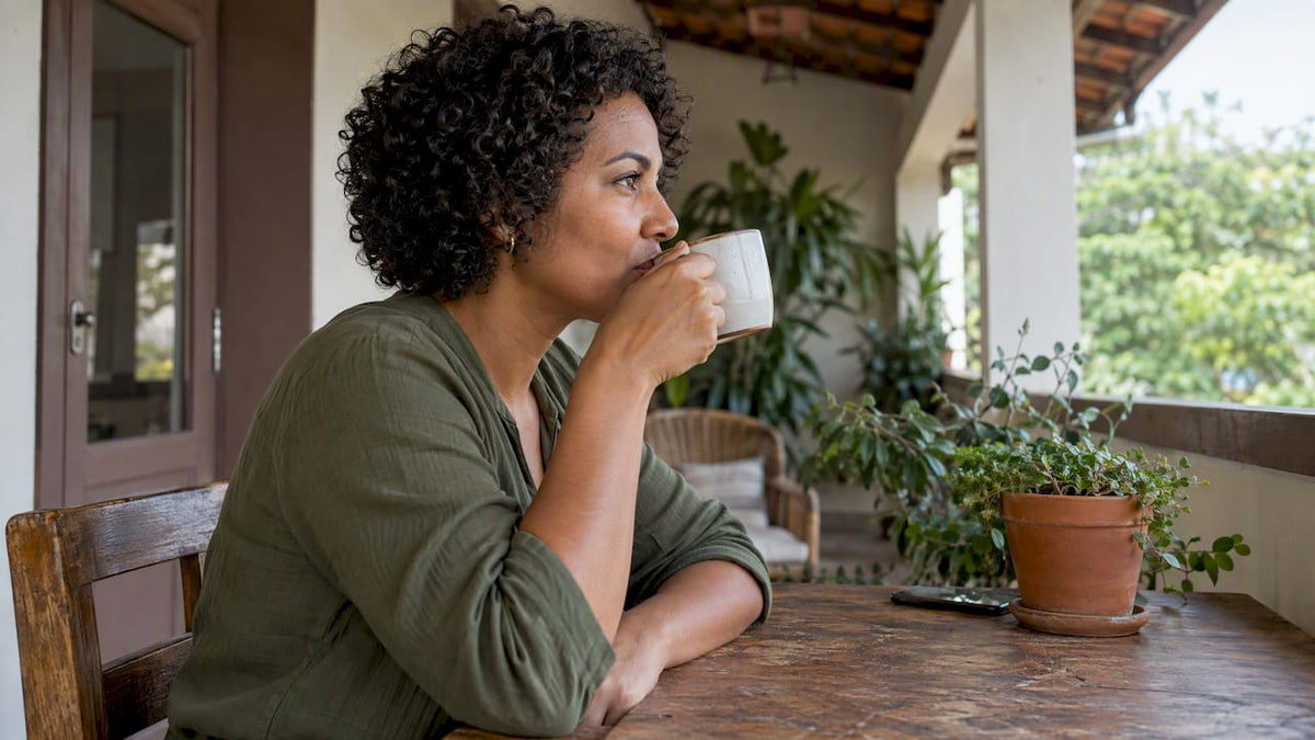Mulher tomando café preto na varanda